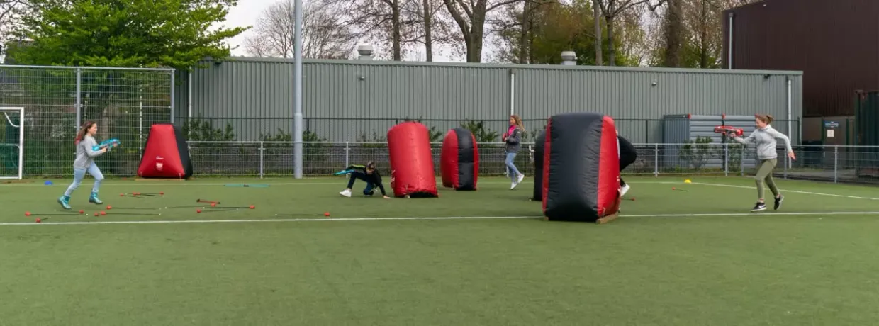 Vier kinderen die samen lasergamen op een grasveld