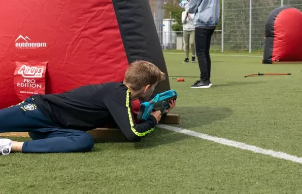 Een kind mikt een lasergun op een kinderfeestje met obstakels op een grasveld
