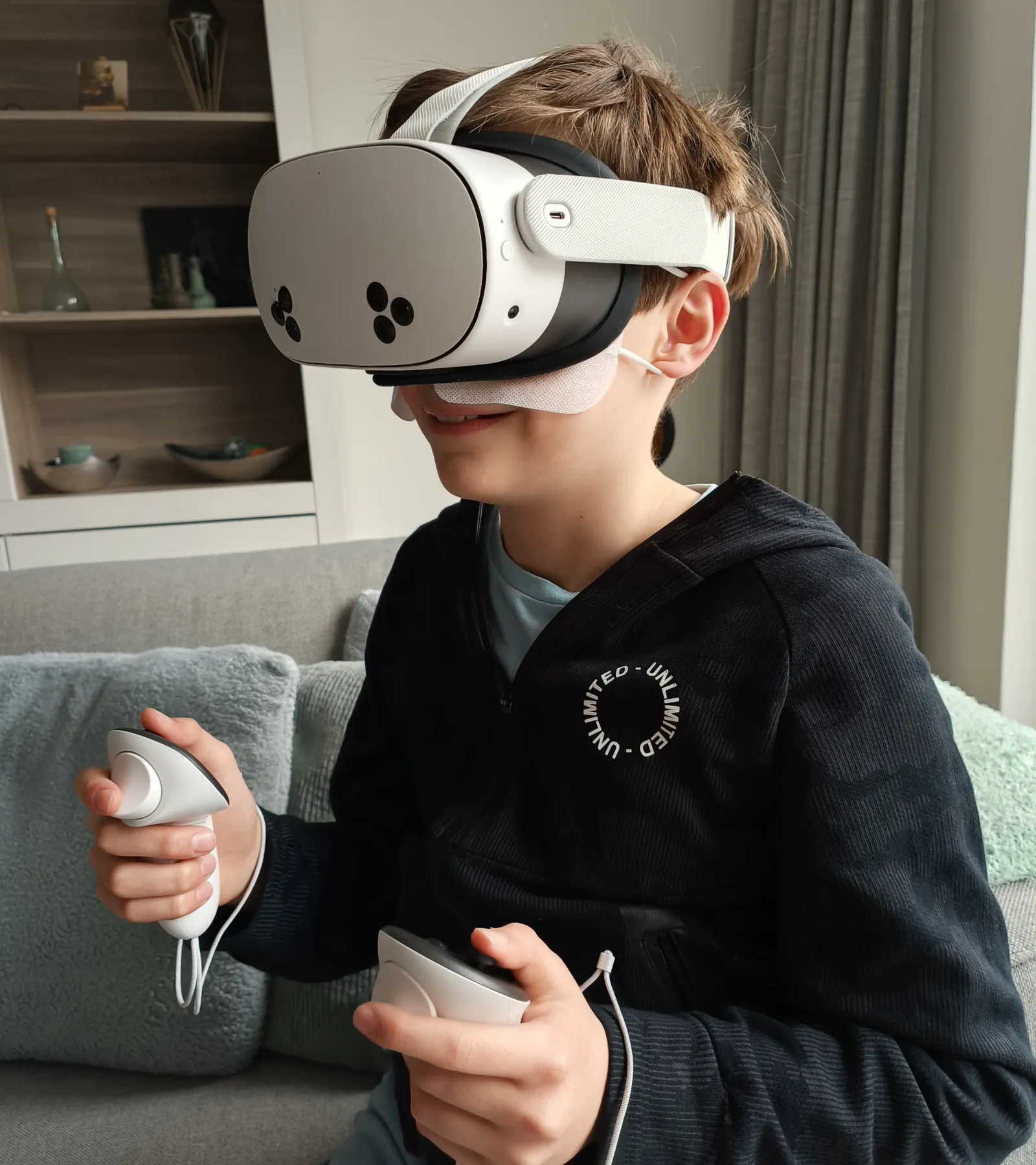 Een kind dat thuis op de bank een VR-bril huurt en speelt met twee controllers