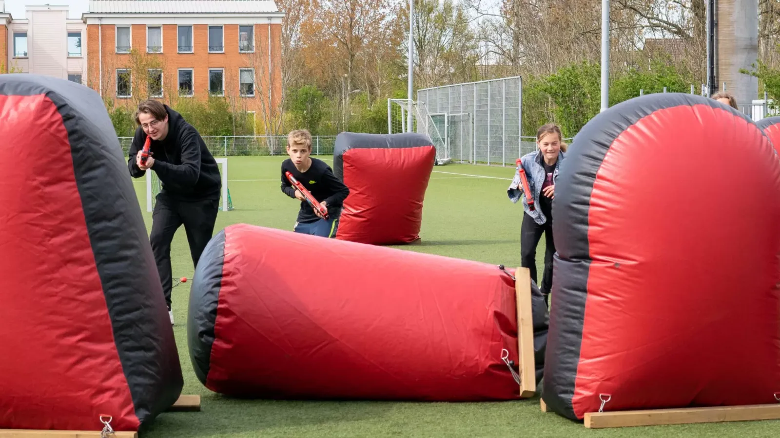 Kinderen spelen lasergame op een veld en overleggen hun tactiek