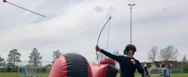 Een speler schiet een pijl van archery tag tijdens een verjaardagsfeest