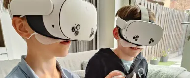 twee kinderen die op de bank thuis een VR-bril spel spelen