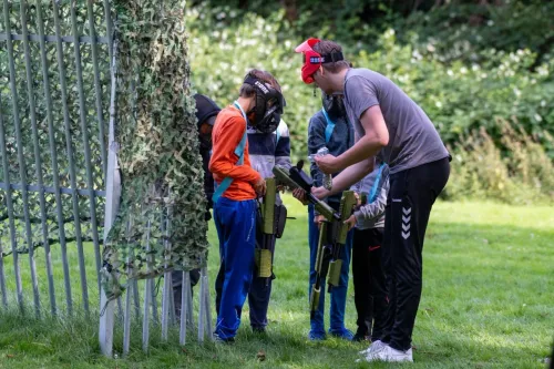 Een volwassene geeft uitleg over paintballen op een kinderfeestje op een grasveld