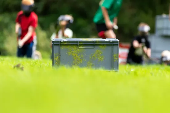 De grijze kist waarin de gehuurde complete paintball set geleverd wordt op een grasveld