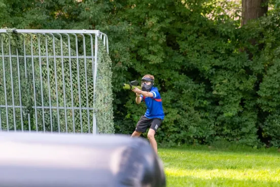 Een speler met een gehuurde paintball set met masker speelt op een voetbalveld buiten