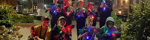 Een groep kinderen die lasergamen op een kinderfeestje in de avond buiten