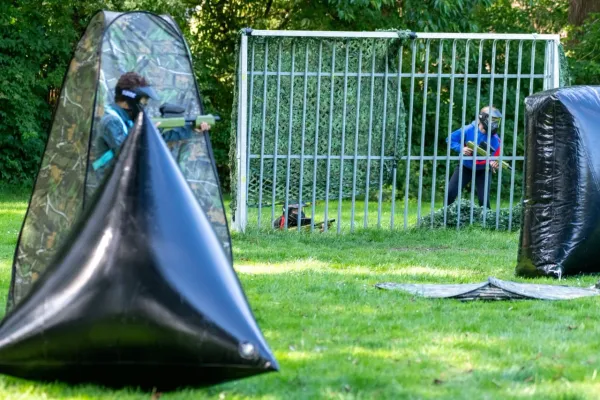 Een speler met masker richt zijn paintball geweer op andere spelers