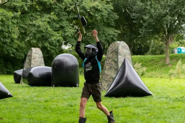 Een speler houdt zijn paintball geweer omhoog omdat hij geraakt is