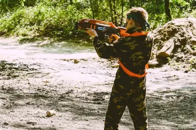 Een kind mikt met een lasergun vanuit dekking in het bos