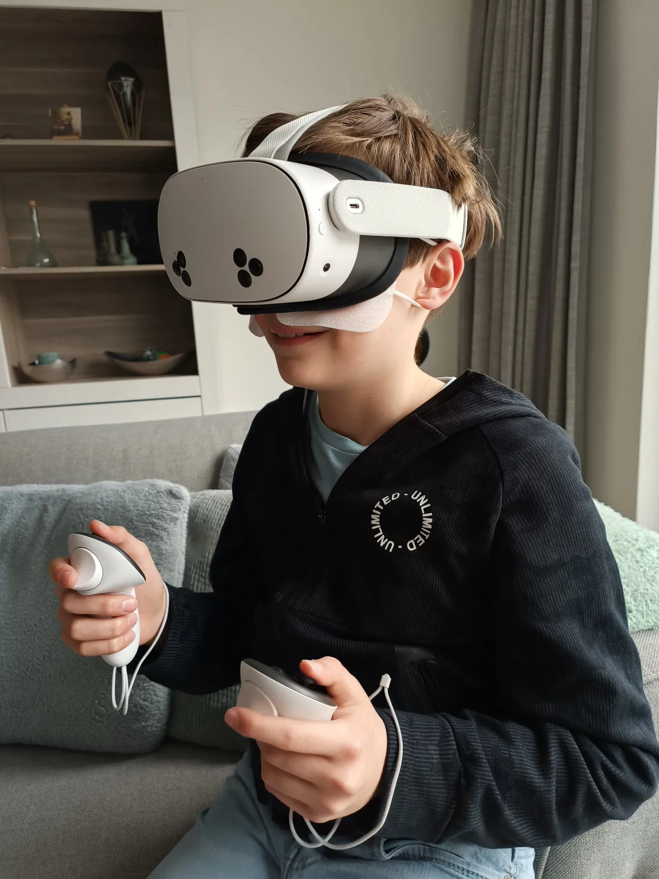 Een kind dat thuis op de bank een VR-bril huurt en speelt met twee controllers