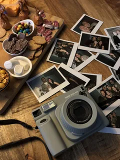 Polaroid camera op tafel met vintage foto's en hapjes